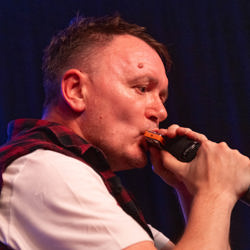 Darren of the Boss and the Beeston street band playing the harmonica on the River by Bruce Springsteen